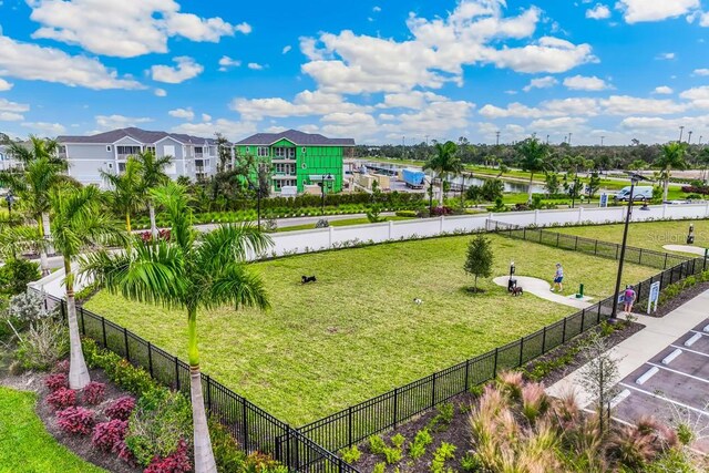 surrounding community with a water view, fence, and a lawn