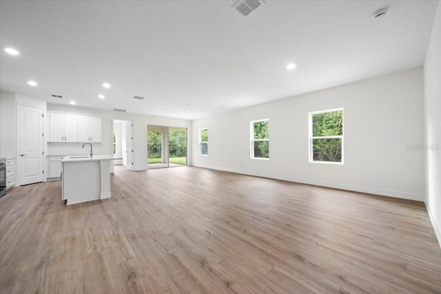 unfurnished living room featuring light wood-type flooring and sink