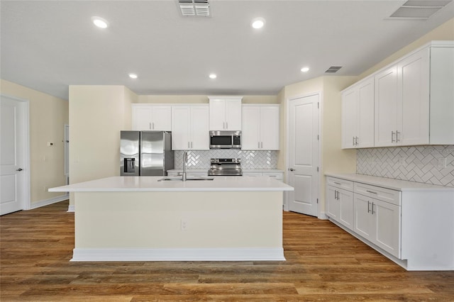 1293 Preston St, Port Charlotte, FL 33952 - kitchen featuring appliances with stainless steel finishes, a center island with sink, decorative backsplash, white cabinets, and recessed lighting