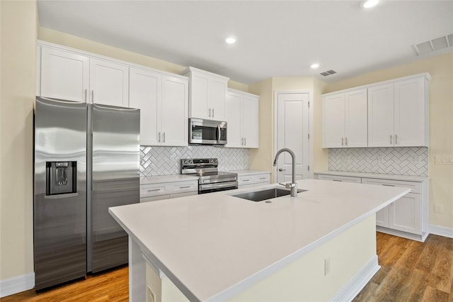 1293 Preston St, Port Charlotte, FL 33952 - kitchen featuring appliances with stainless steel finishes, light wood-type flooring, white cabinetry, tasteful backsplash, and recessed lighting