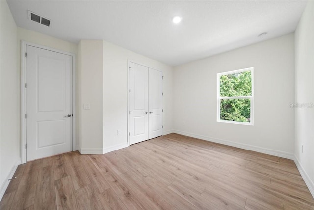 unfurnished bedroom with light wood finished floors, baseboards, visible vents, and a closet