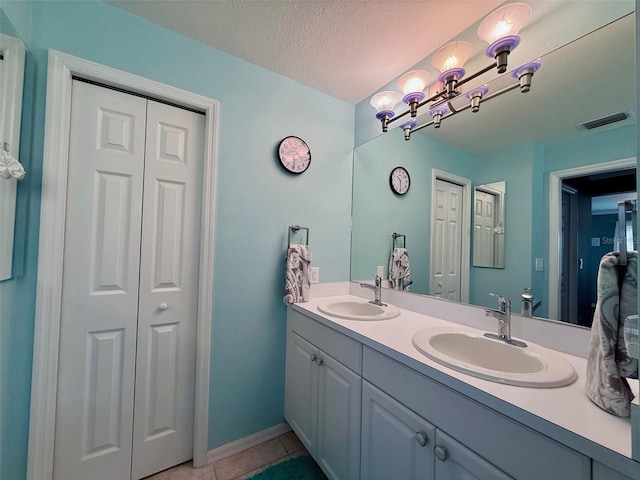 bathroom featuring tile patterned flooring, vanity, and a textured ceiling