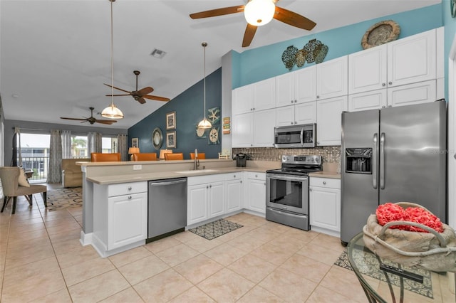 kitchen with sink, stainless steel appliances, kitchen peninsula, pendant lighting, and white cabinets