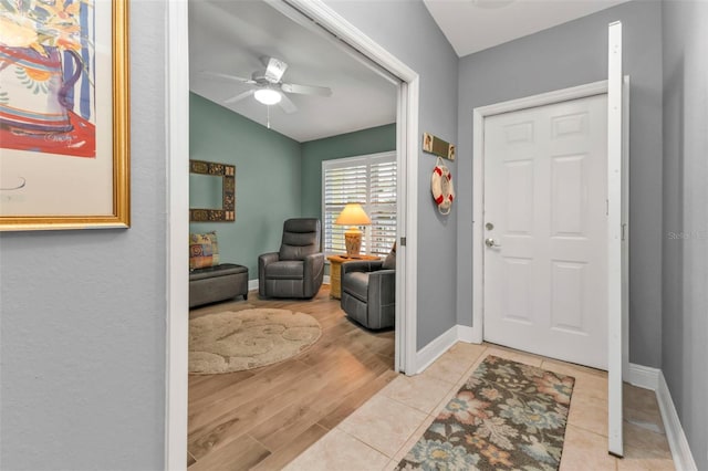 foyer entrance featuring ceiling fan, light hardwood / wood-style floors, and vaulted ceiling