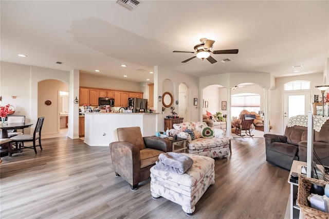 living room featuring hardwood / wood-style floors, ceiling fan, and decorative columns