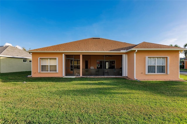 rear view of house with a lawn and a sunroom