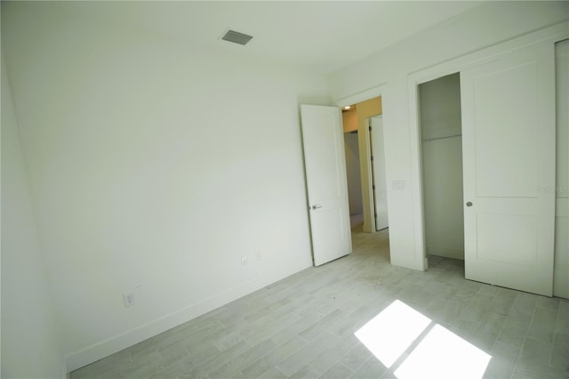 unfurnished bedroom with light hardwood / wood-style flooring and a closet