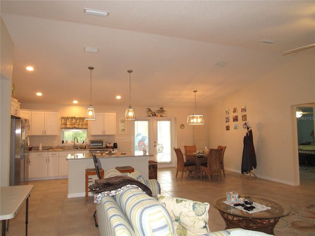 living room with light tile patterned floors, an inviting chandelier, and lofted ceiling