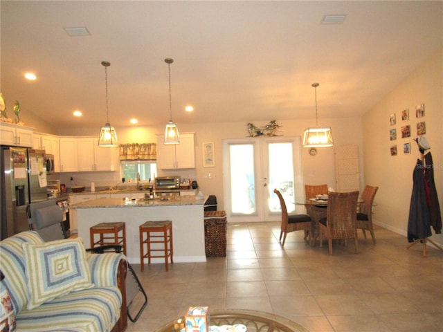 tiled living room featuring vaulted ceiling and french doors