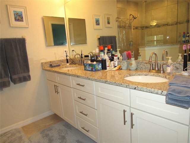 bathroom featuring tile patterned flooring, tiled shower, and vanity