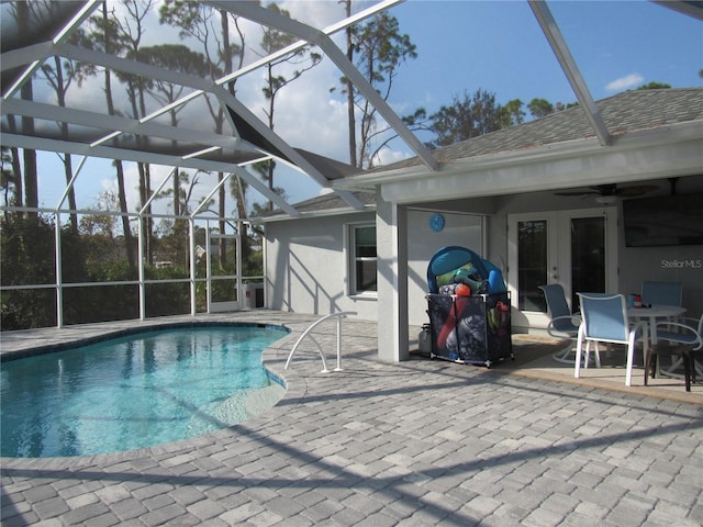 view of pool with glass enclosure, a patio, and ceiling fan