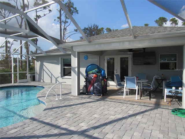 view of pool featuring glass enclosure, a patio, and ceiling fan