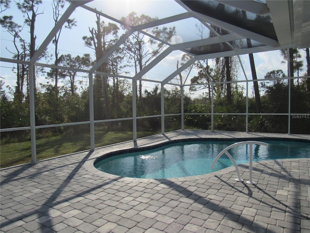 view of pool featuring glass enclosure and a patio area