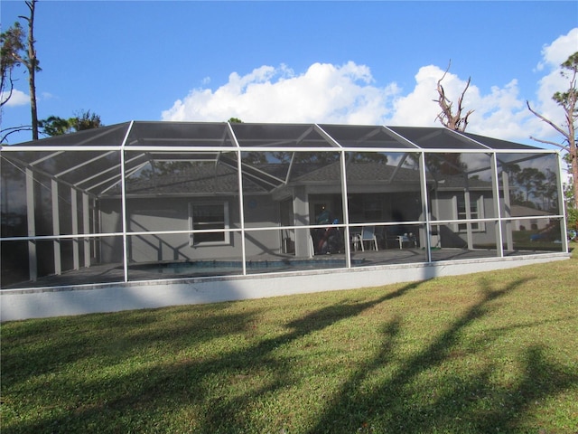 rear view of house featuring glass enclosure and a lawn