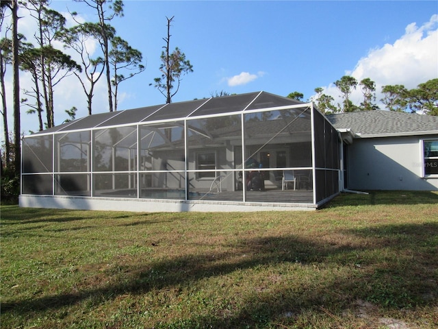 back of house with glass enclosure and a yard