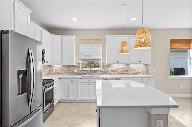 kitchen with stainless steel appliances, hanging light fixtures, white cabinets, and sink