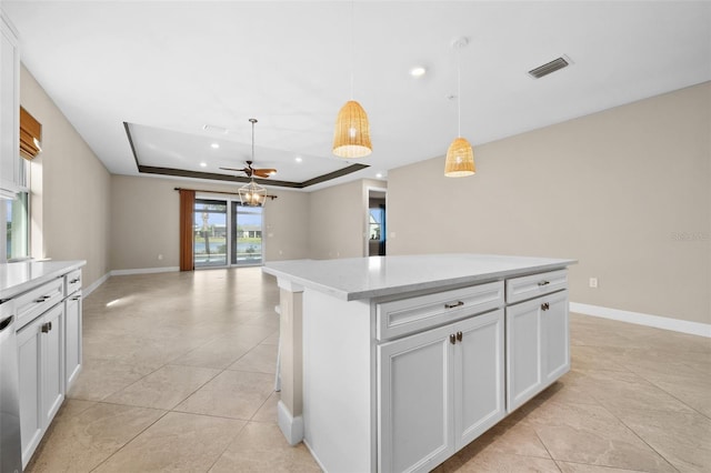 kitchen with pendant lighting, white cabinetry, a center island, and a tray ceiling