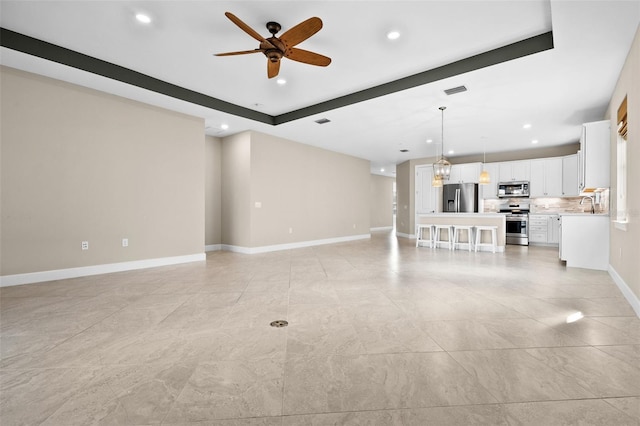 unfurnished living room featuring ceiling fan and sink