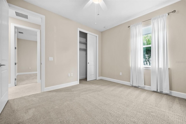 unfurnished bedroom with ceiling fan, light carpet, and a closet