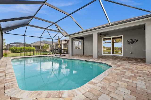 view of swimming pool featuring glass enclosure, ceiling fan, and a patio