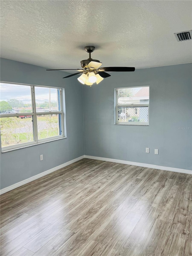 empty room with ceiling fan, a textured ceiling, and light hardwood / wood-style flooring