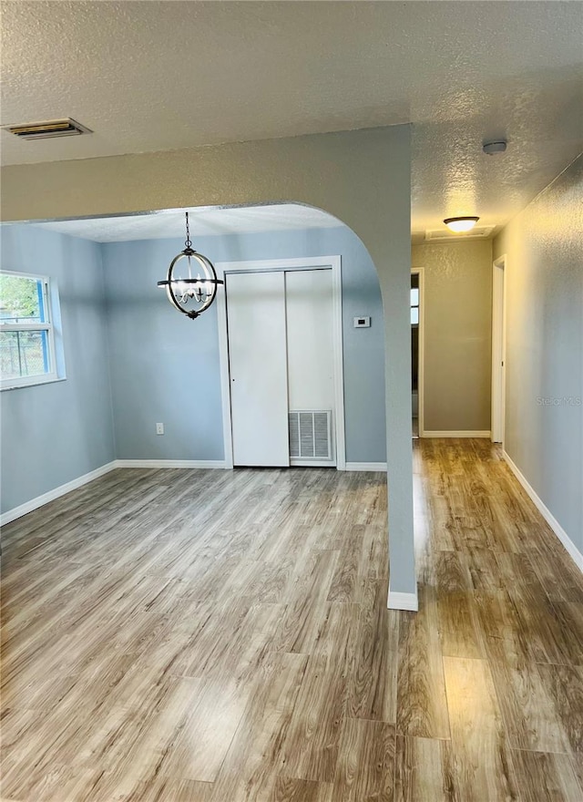 spare room with wood-type flooring, a textured ceiling, and an inviting chandelier