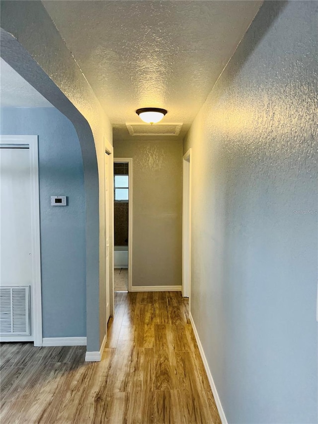 corridor featuring a textured ceiling and hardwood / wood-style flooring