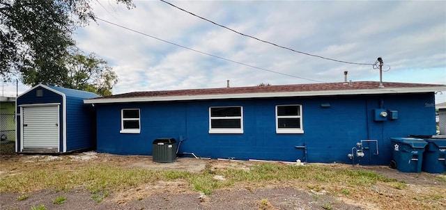 back of property with central AC unit and a storage shed