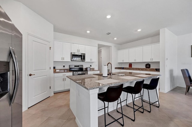 kitchen with a center island with sink, appliances with stainless steel finishes, and white cabinets