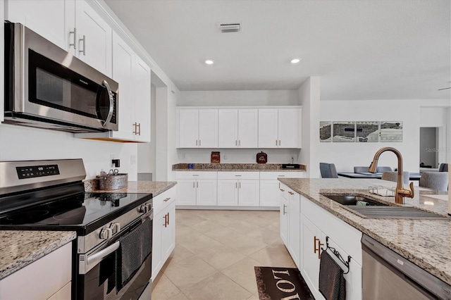 kitchen with light stone countertops, sink, appliances with stainless steel finishes, and white cabinets