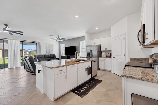 kitchen with appliances with stainless steel finishes, sink, an island with sink, white cabinets, and light stone counters