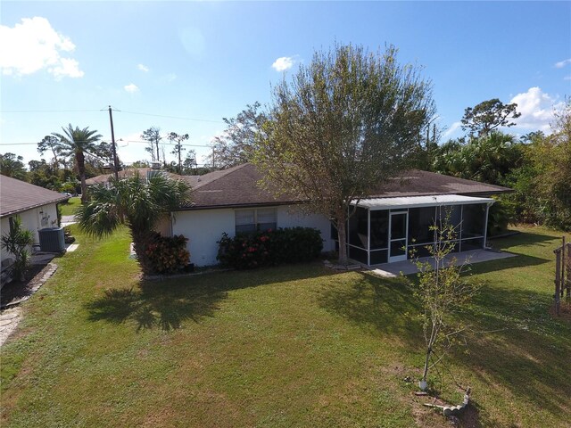 rear view of house with a yard, central AC, and a sunroom