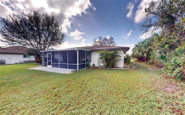 rear view of property with a yard, a patio, and a sunroom