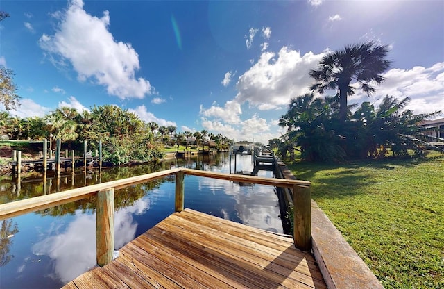 dock area with a lawn and a water view