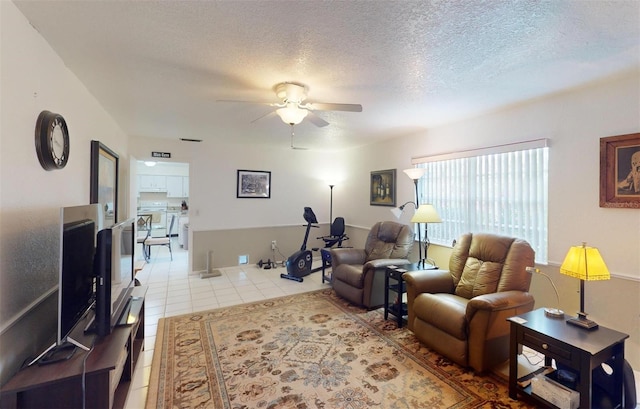 living room with ceiling fan, light tile patterned floors, and a textured ceiling