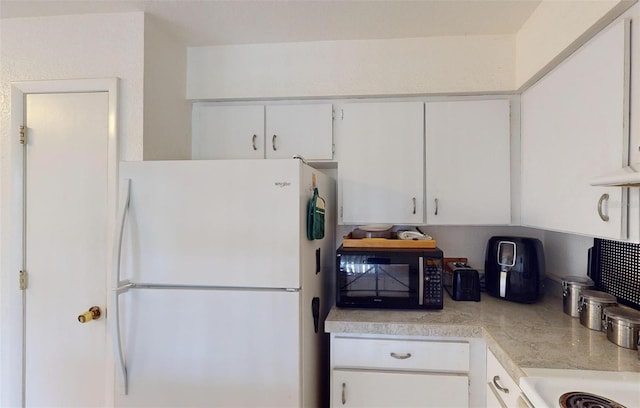 kitchen featuring white refrigerator and white cabinetry