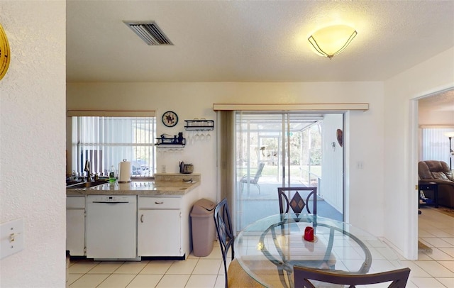 dining space featuring sink, light tile patterned flooring, and a textured ceiling