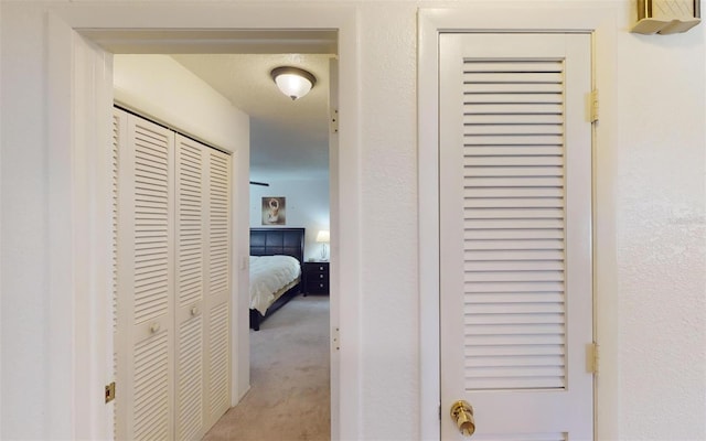 hallway featuring light carpet and a textured ceiling