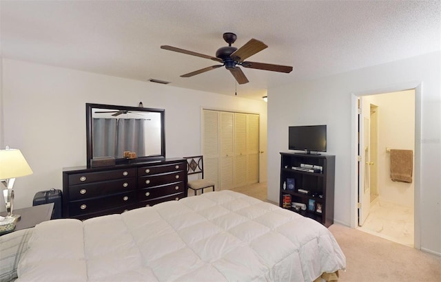 bedroom with carpet, a textured ceiling, ceiling fan, connected bathroom, and a closet