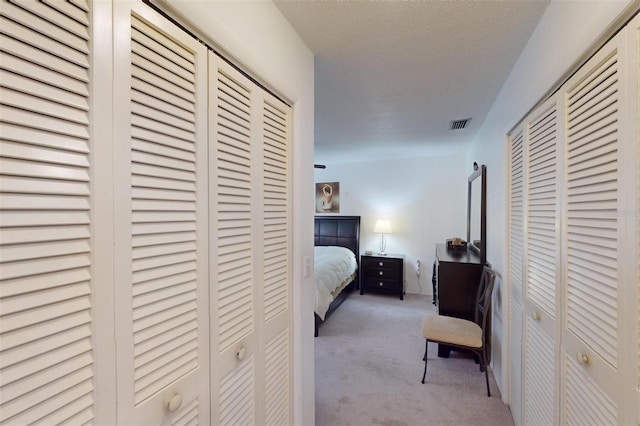 carpeted bedroom with a textured ceiling and two closets