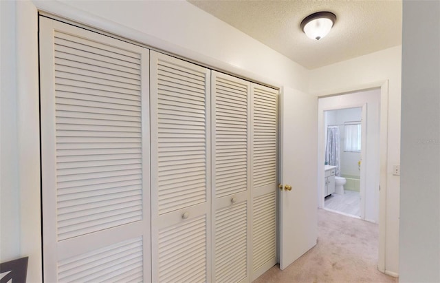 hallway featuring light colored carpet and a textured ceiling