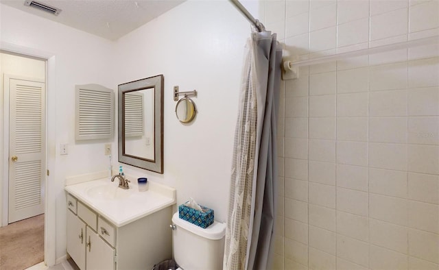 bathroom with vanity, toilet, and a textured ceiling