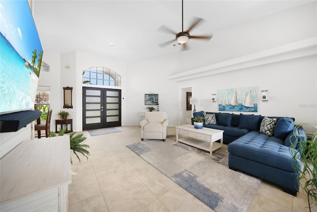 tiled living room with ceiling fan and a high ceiling