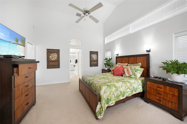 bedroom with high vaulted ceiling, ensuite bath, ceiling fan, and light colored carpet