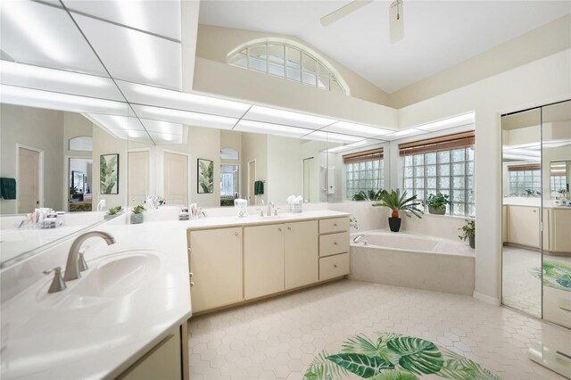 bathroom featuring a wealth of natural light, a bathtub, vanity, and vaulted ceiling