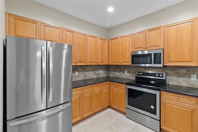 kitchen with stainless steel appliances, light tile patterned flooring, dark stone counters, and tasteful backsplash