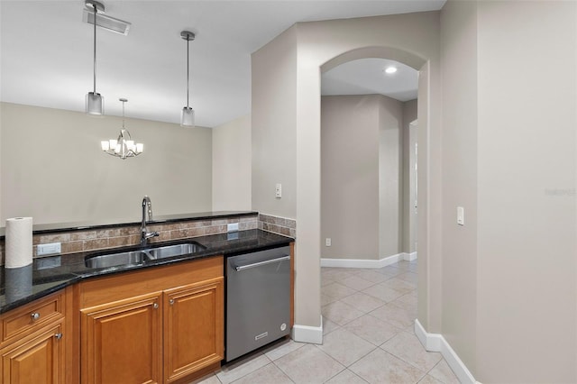 kitchen featuring sink, dark stone counters, light tile patterned floors, pendant lighting, and dishwasher