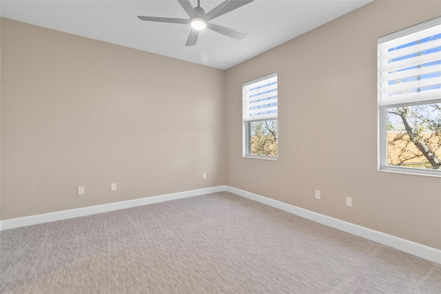 unfurnished room with a wealth of natural light, light colored carpet, and ceiling fan