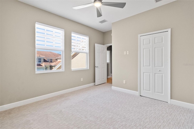 unfurnished bedroom with a closet, light colored carpet, and ceiling fan