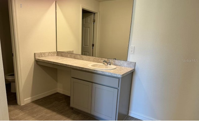 bathroom with toilet, vanity, and hardwood / wood-style flooring